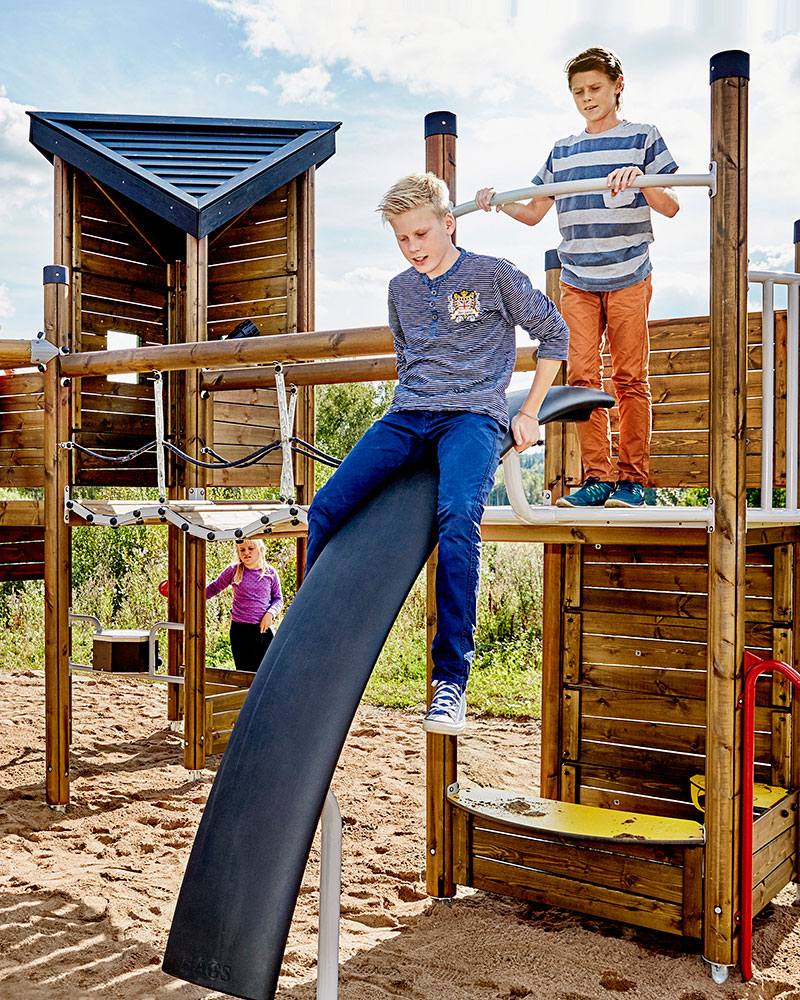 Older children playing on a large wooden playground unit.